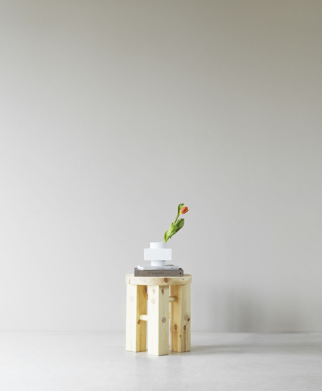 Fyr Stool Hocker von Normann Copenhagen aus hellem Holz mit Vase und Tulpe.