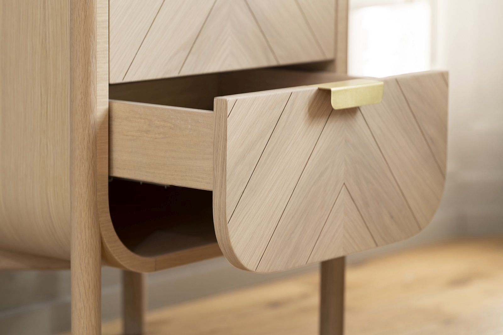 Detailaufnahme der Hartô Marius Kommode aus Eichenholz mit offener Schublade und goldenem Griff.