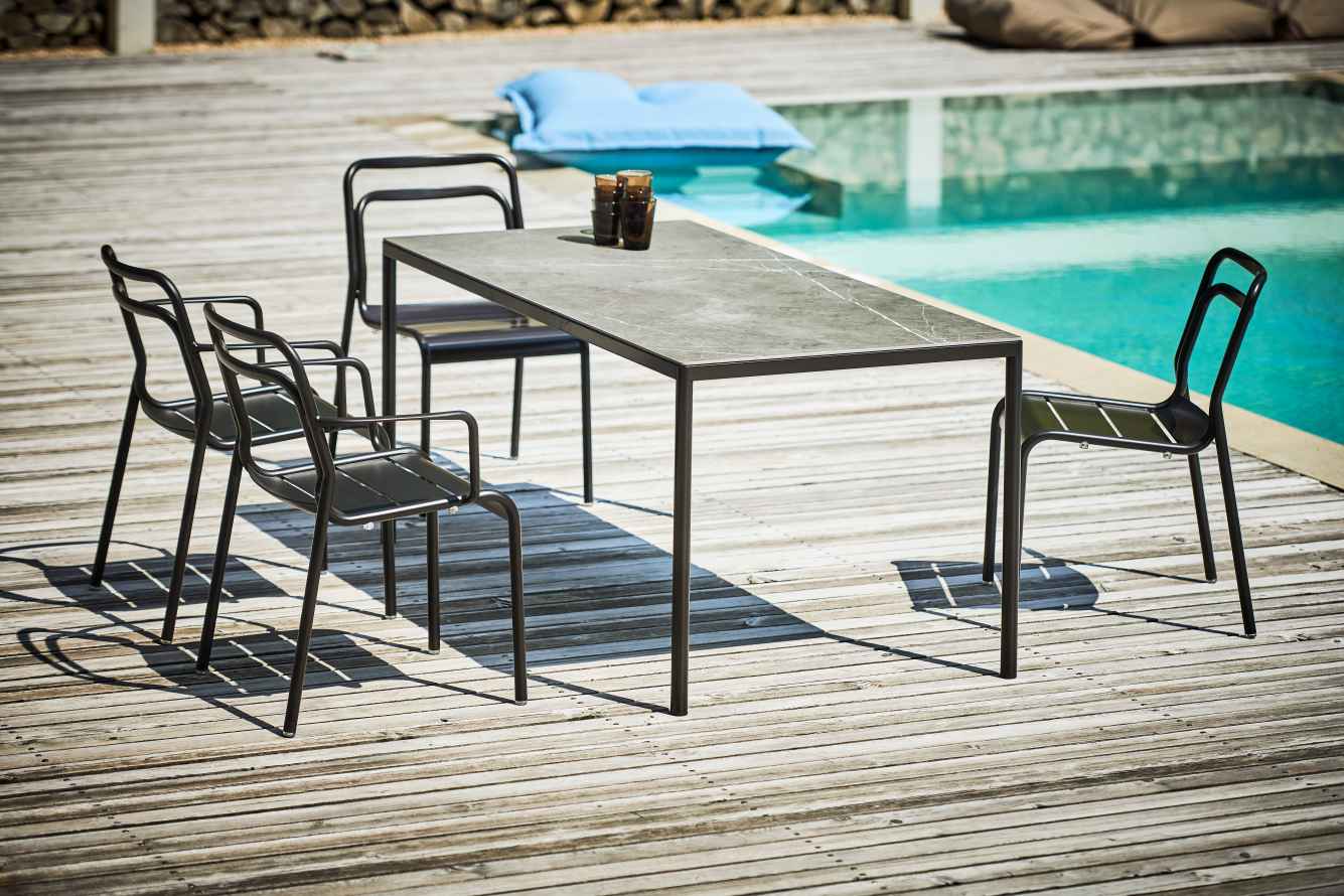 Live Stapelstuhl von Jan Kurtz: Schwarze Outdoor Stühle und Tisch auf Holzterrasse am Pool.