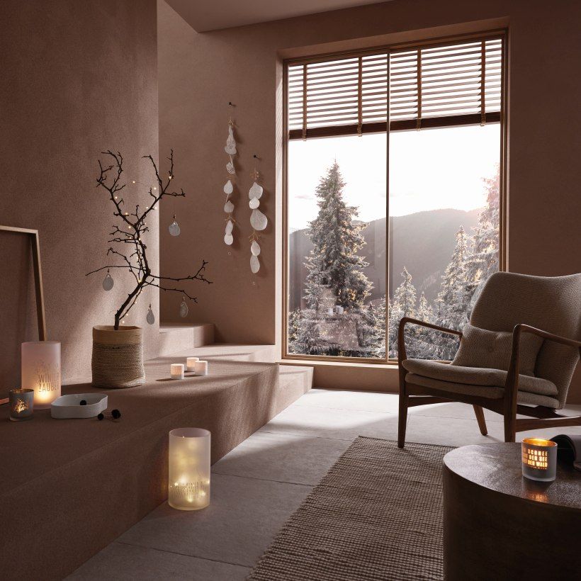 Winterliche Wohnrauminszenierung mit Räder Windlicht "Winterzauber", Dekoration, Kerzen und Blick auf verschneite Berge.