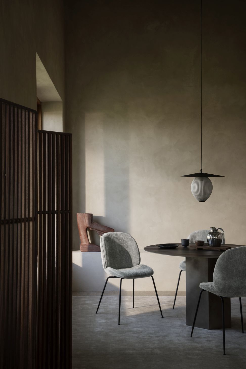 Runder Esstisch aus Stahl von Gubi mit Stühlen und Pendelleuchte in minimalistischem Interieur.