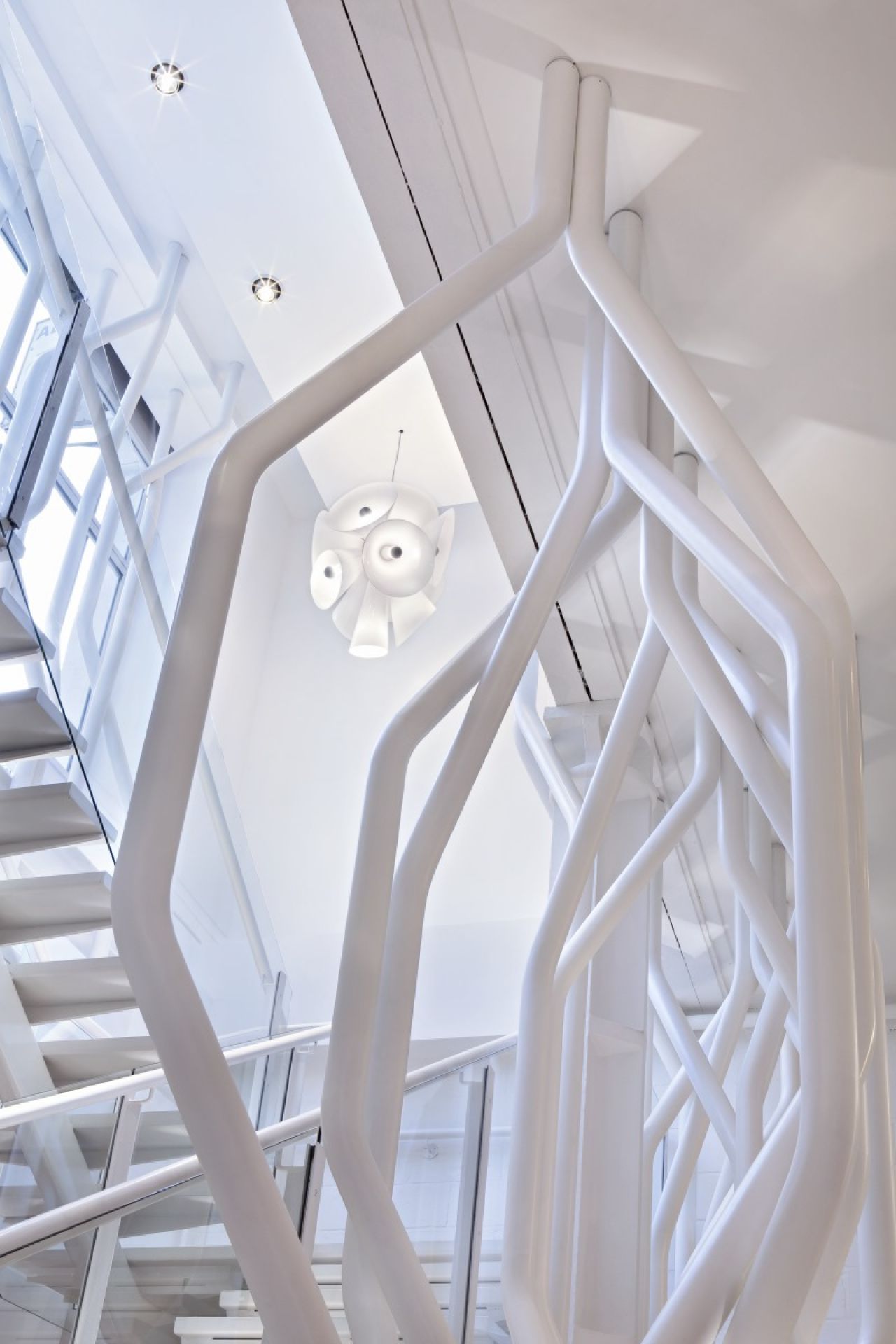Weiße Nebula Pendelleuchte von Flos, gesehen durch ein weißes Treppengeländer, modernes Design.