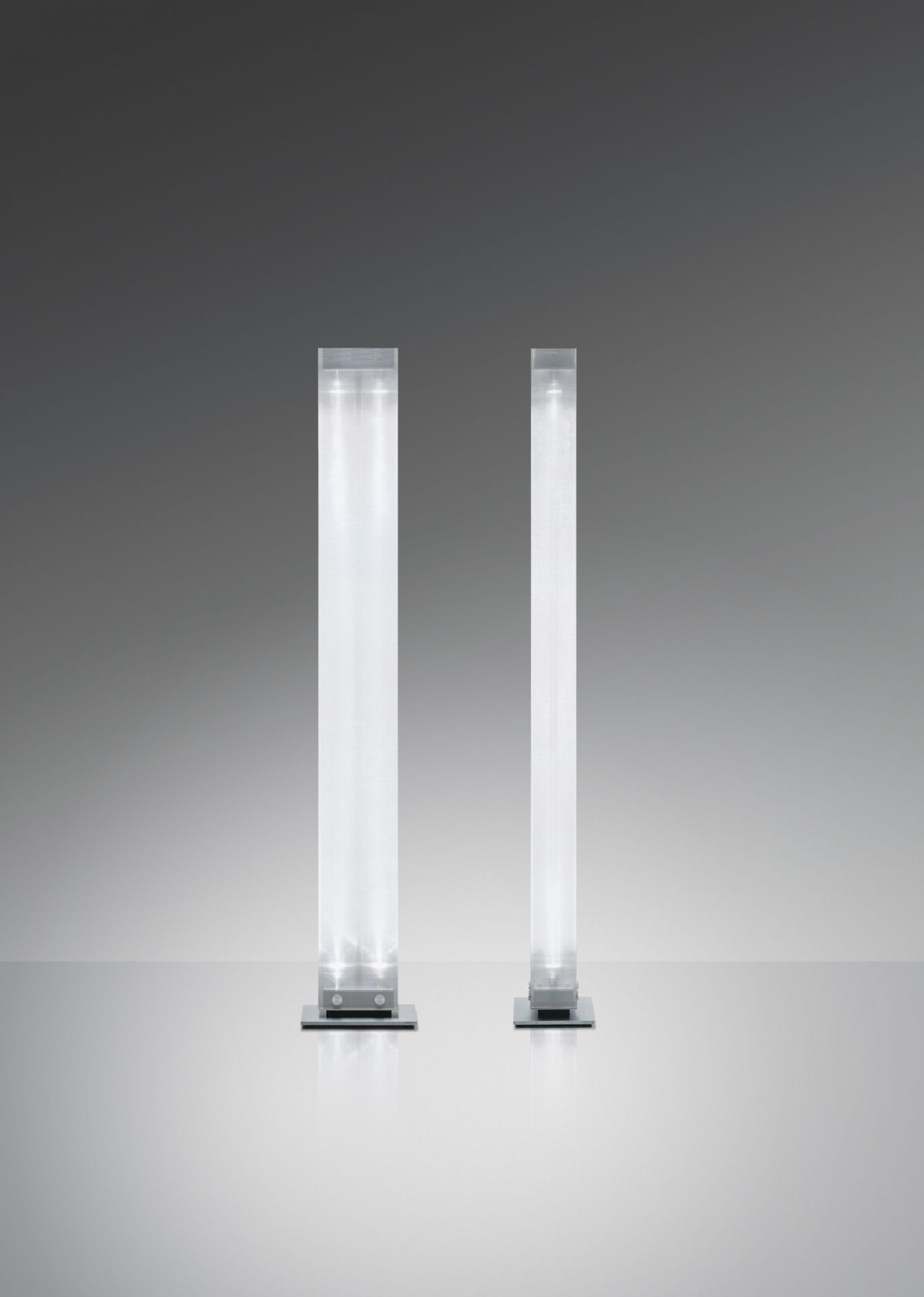 Zwei Twilight LED Stehleuchten von Belux in unterschiedlichen Größen auf grauem Hintergrund.