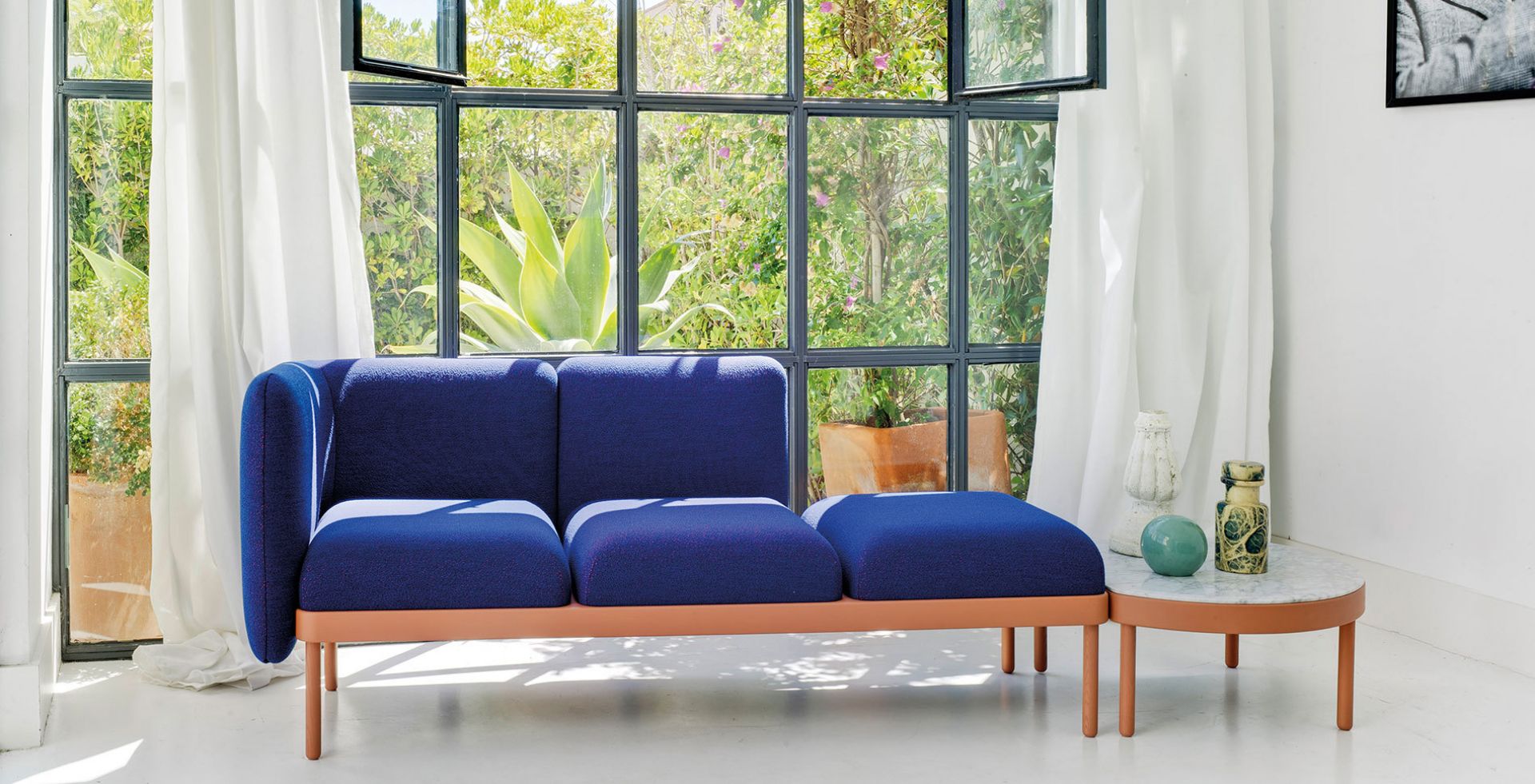 Mosaico Sitzbank von Sancal, blaues modulares Sofa mit Beistelltisch vor Fenster.
