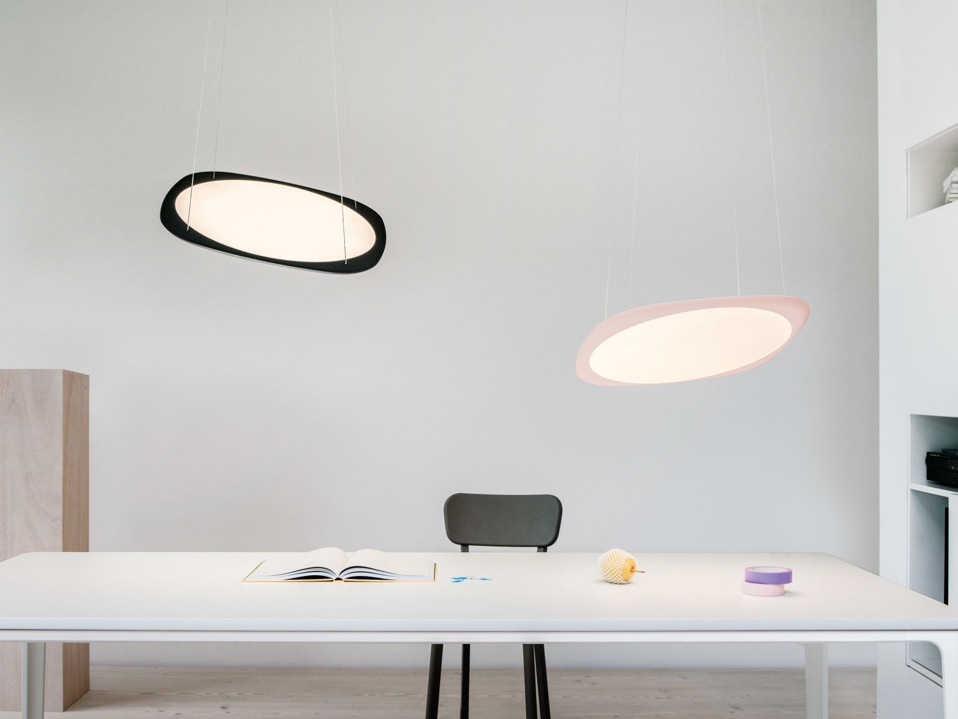 Zwei Flying Pendelleuchten von Tobias Grau in Schwarz und Rosa über einem Schreibtisch.