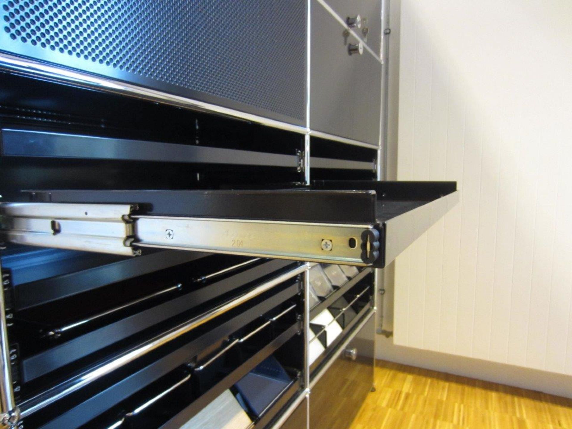 Detailaufnahme eines schwarzen USM Haller Ausziehtablars, ein Ersatzteil für modulare Möbel, mit silbernen Führungsschienen.