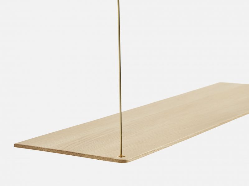 Detailaufnahme eines hellen Stedge Add-on Regalbords aus Holz mit goldener Aufhängung.