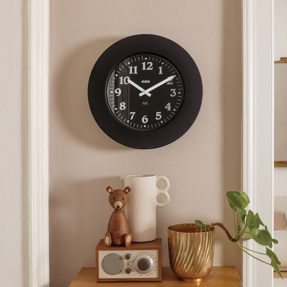 Schwarze Alessi Wanduhr "Momento 11 B" an der Wand, stilvolle Dekoration für Wohnzimmer und Küche.