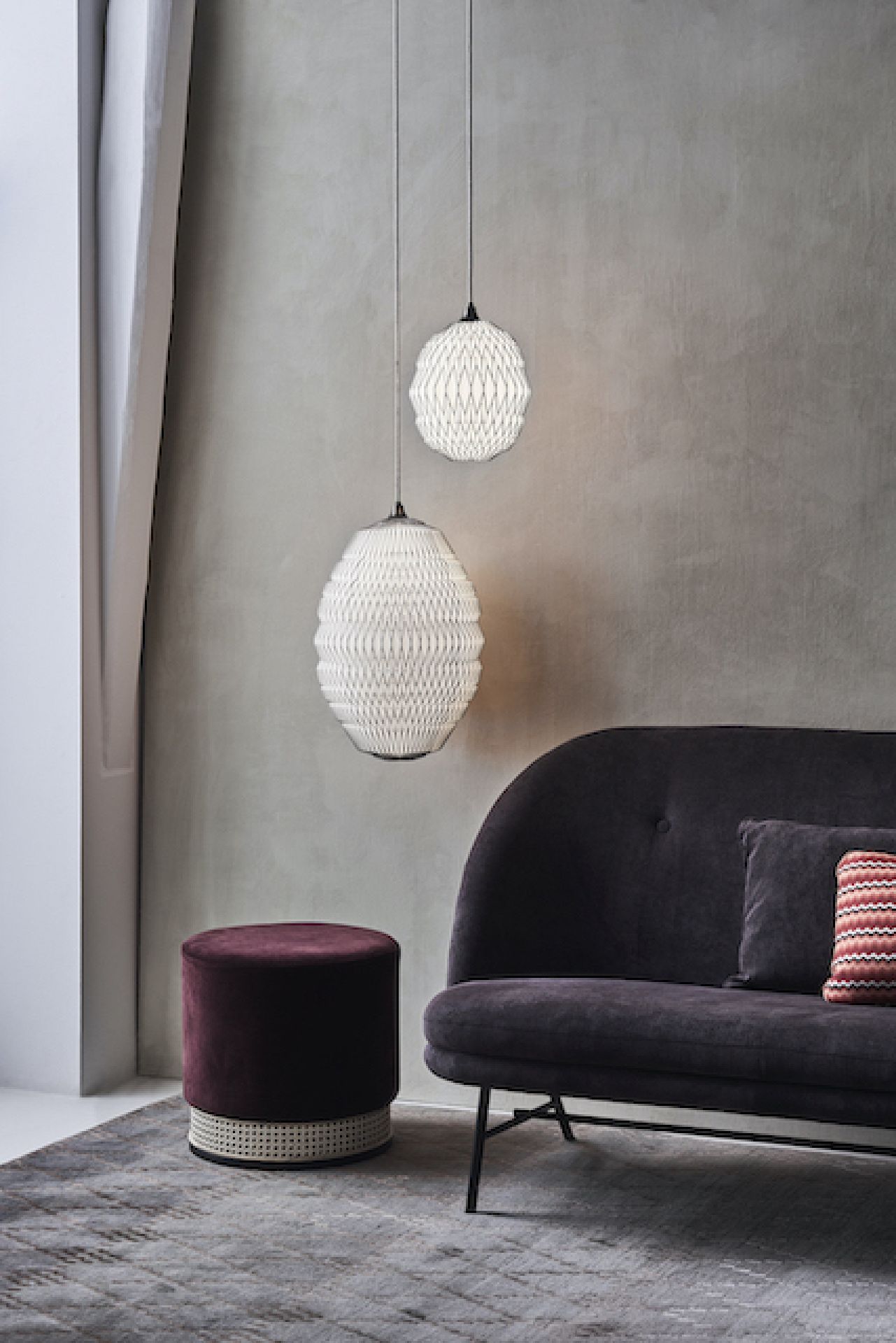 Zwei CALEO Pendelleuchten von Le Klint hängen über einem Sofa in einem Wohnzimmer.