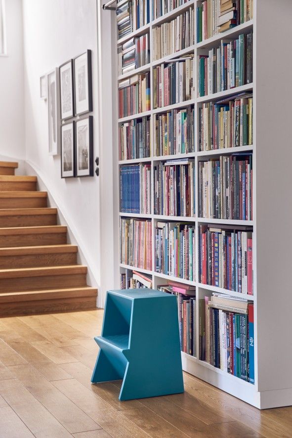 Blauer Tritthocker von Richard Lampert vor Bücherregal und Treppe. Design Tritthocker für Kinder.