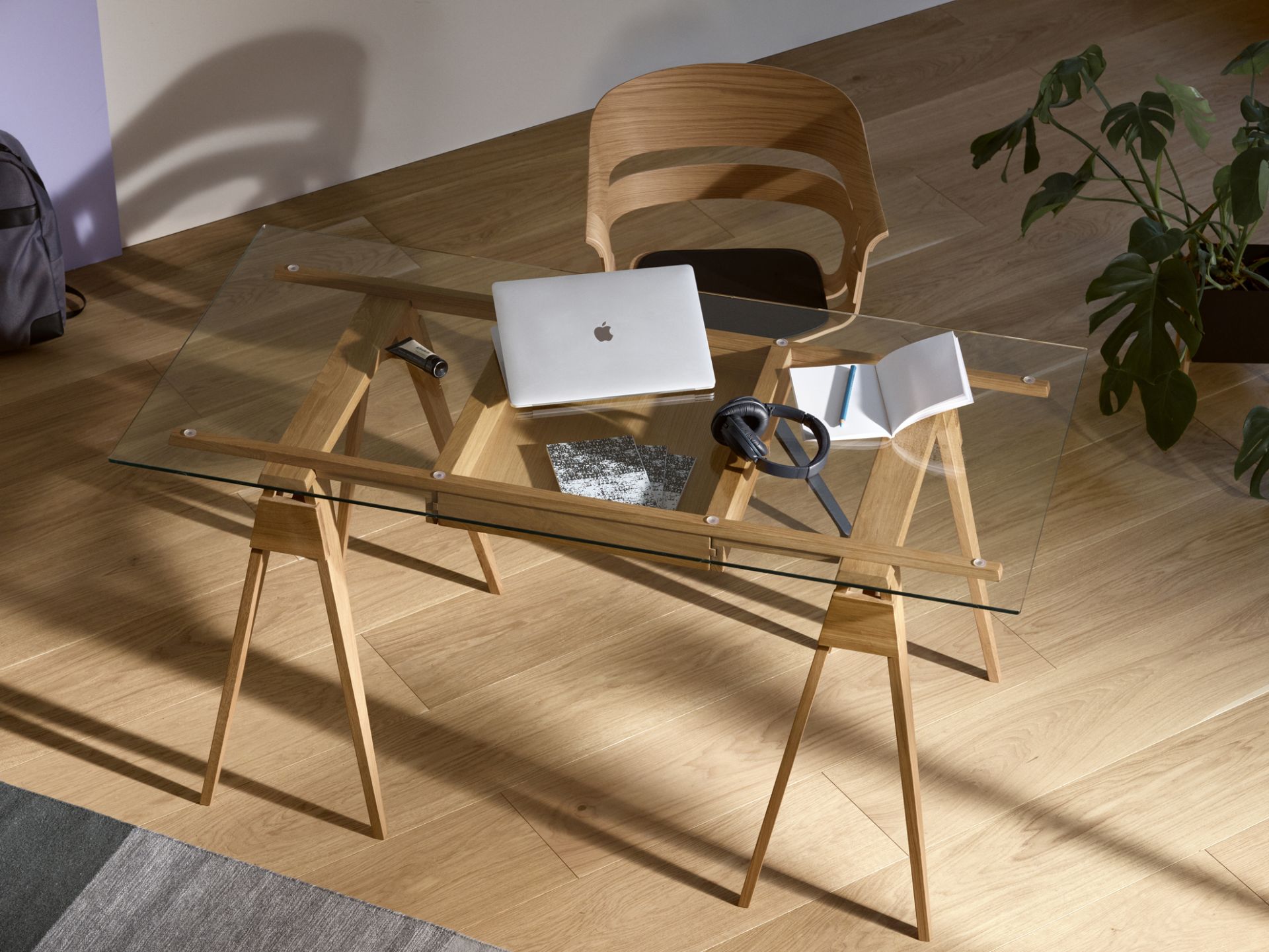 Arco Desk von Design House Stockholm: Glas-Schreibtisch mit Holzgestell, Laptop, Kopfhörer und Notizbuch.