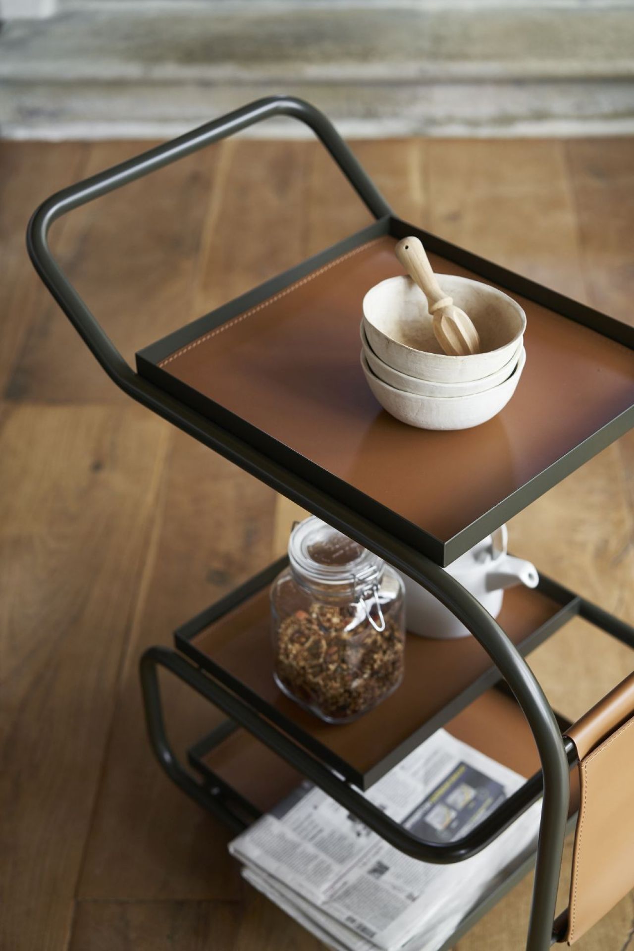 Zenzero Servierwagen: Moderner Barwagen mit goldenem Gestell und braunen Ablageflächen, dekoriert mit Schalen und Vorratsgläsern.