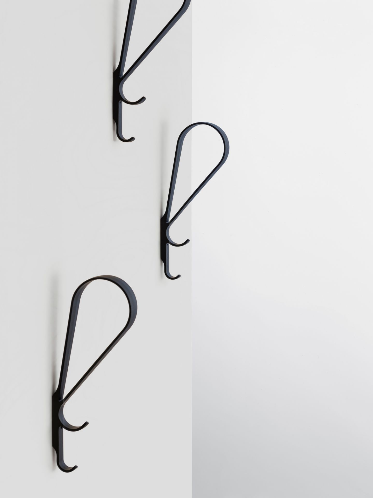 Drei schwarze Artek Tupla Wandhaken an einer weißen Wand, modernes skandinavisches Design für Garderobe und Aufbewahrung.