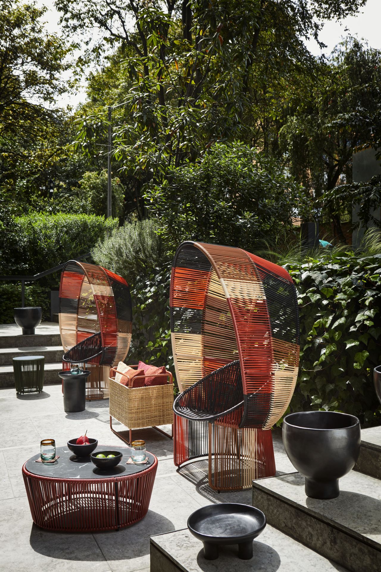 Cartagena Reina Outdoor Sessel: Zwei farbenfrohe Korbsessel mit passendem Tisch und Deko im Garten.