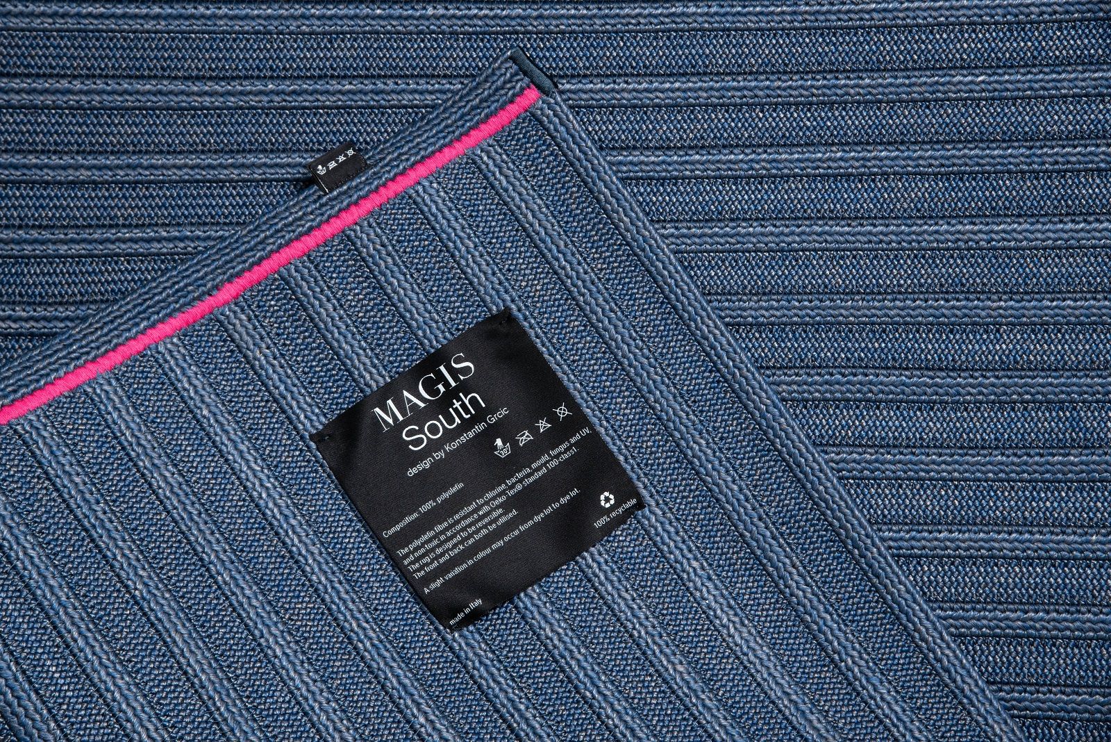 Detailaufnahme des blauen South Teppichs von Magis mit feiner Rippenstruktur und pinkfarbenem Akzent.