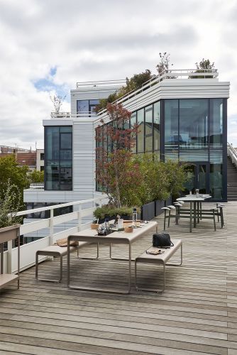 Bolder 2-Sitzer Tisch mit Sitzflächen von Fermob für den Outdoor-Bereich auf einer Dachterrasse.