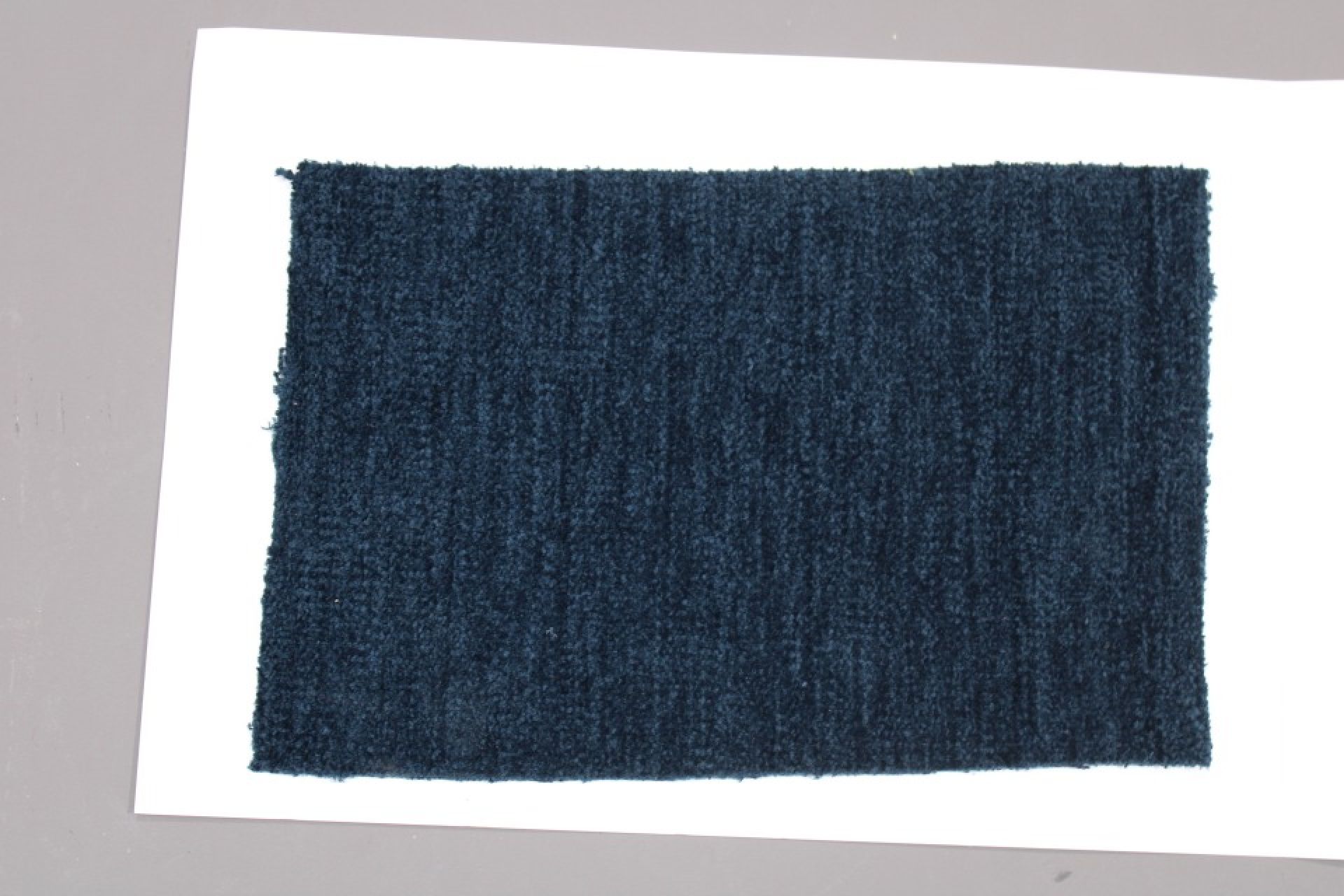 Stoffmusterkarte Gruppe 81 Cor: Nahaufnahme eines dunkelblauen, texturierten Möbelstoffes für Polster und Dekoration.
