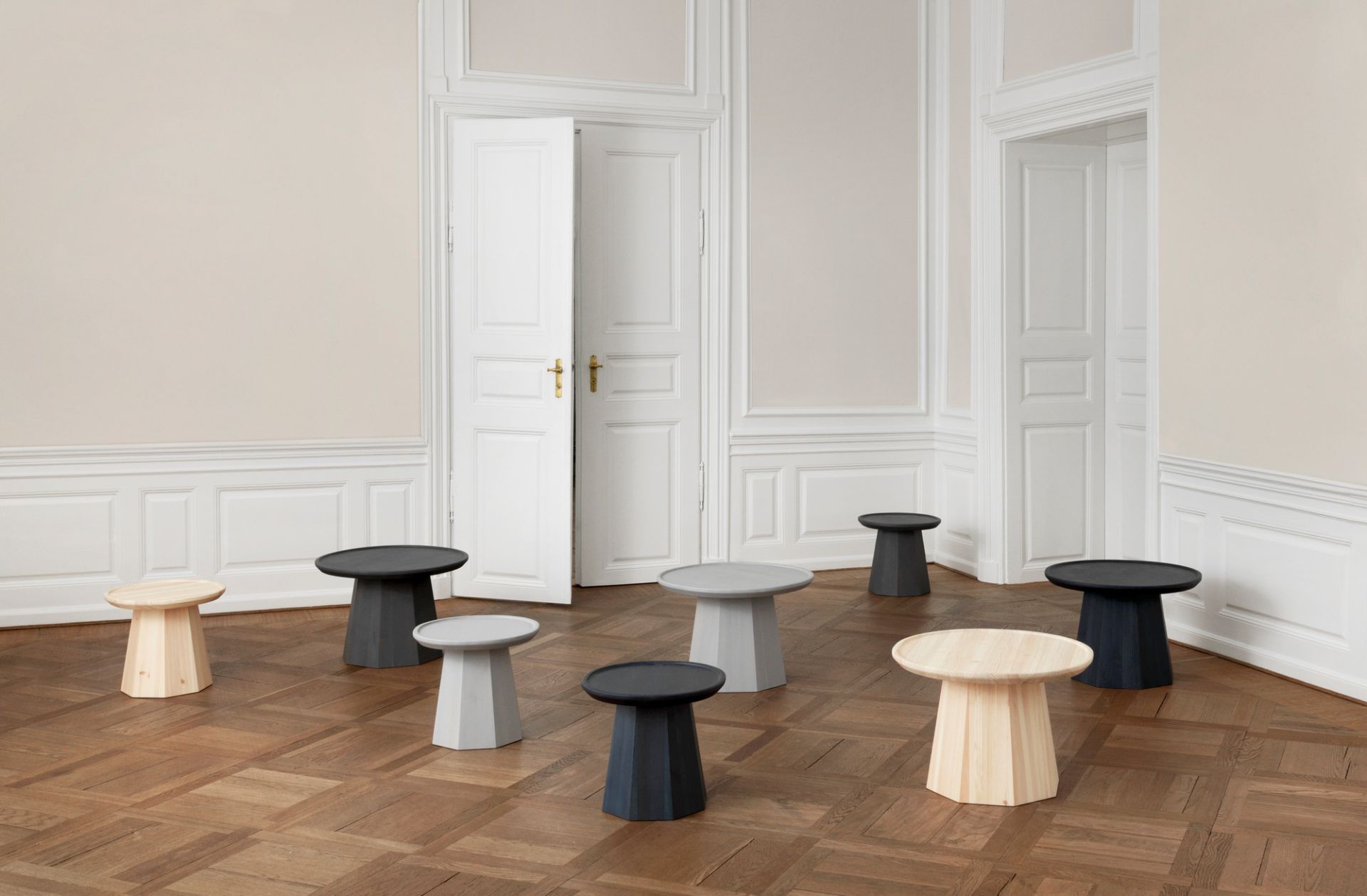 Gruppe von Normann Copenhagen Pine Table Beistelltischen in verschiedenen Farben auf Parkettboden.