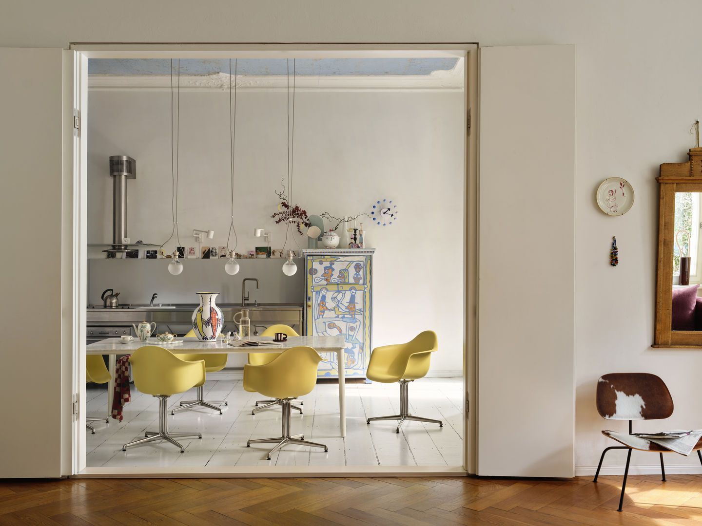 Gelber Eames Plastic Arm Chair DAL mit Sitzpolster von Vitra am Esstisch in Küche.