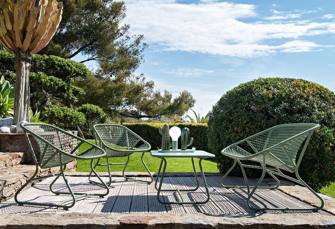 Grüne Sixties Outdoor Bank von Fermob mit passendem Tisch im Garten.