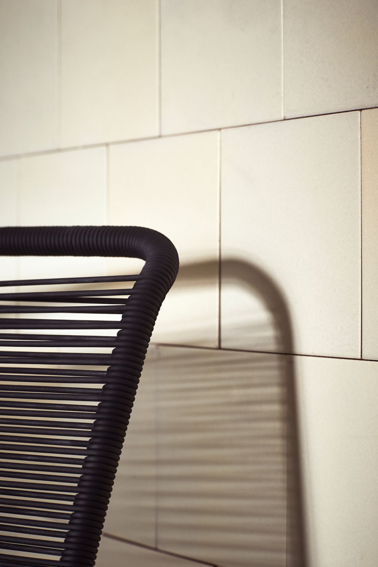 Detailaufnahme: Schwarzer Panton One Stuhl mit Schnurgeflecht vor hellem Hintergrund. Design Stuhl.