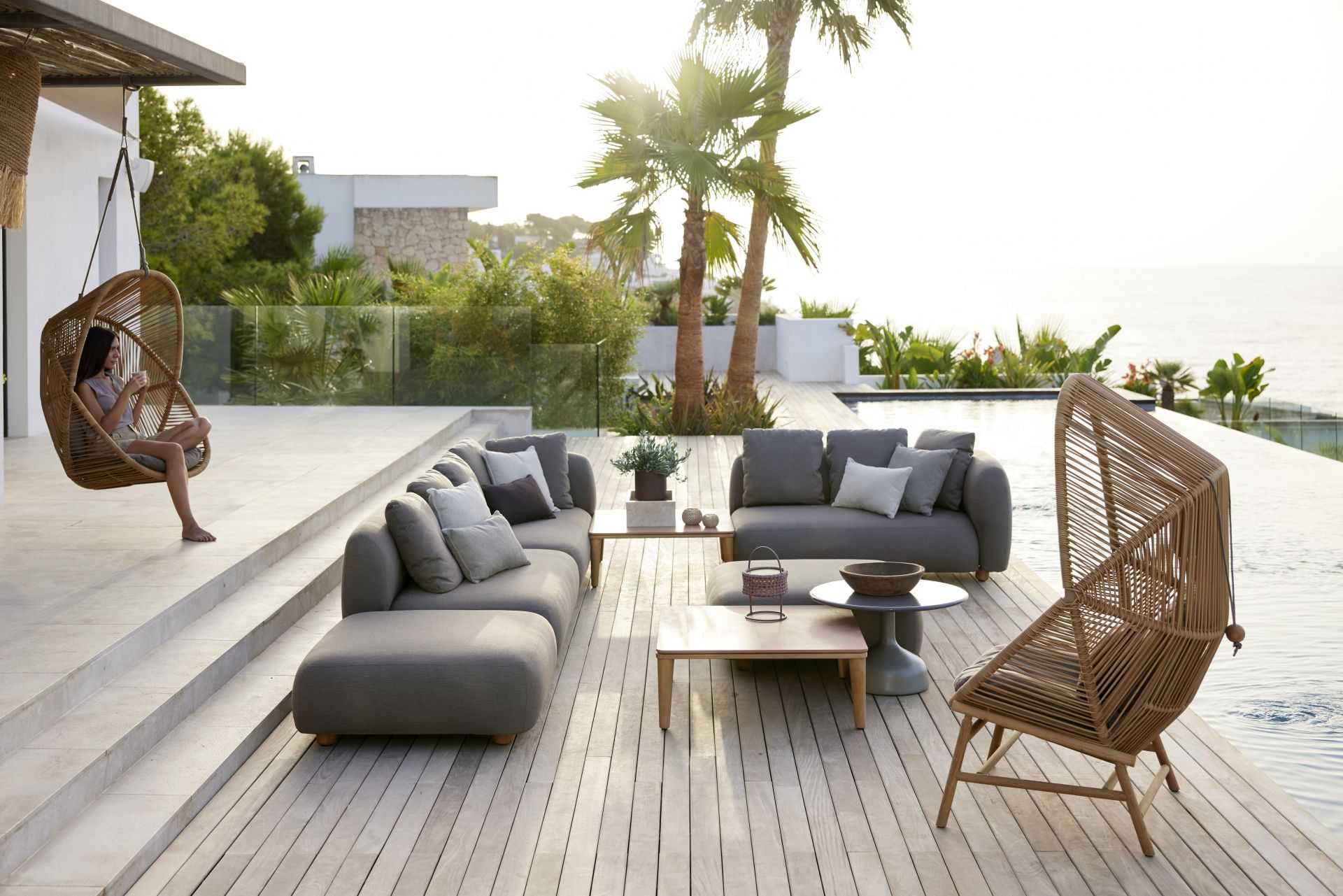 Capture Outdoor 2-Sitzer Sofa Modul von Cane-Line auf einer sonnigen Terrasse mit Pool.