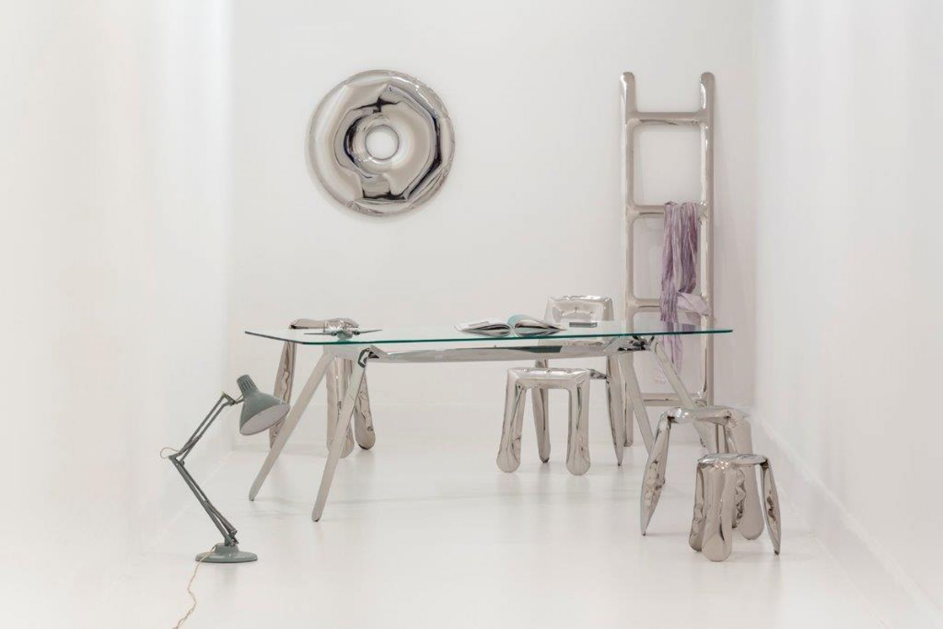 Silberner Zieta Herrendiener mit Schreibtisch, Stühlen, Leiter und Wanddekoration in minimalistischem, weißem Raum.