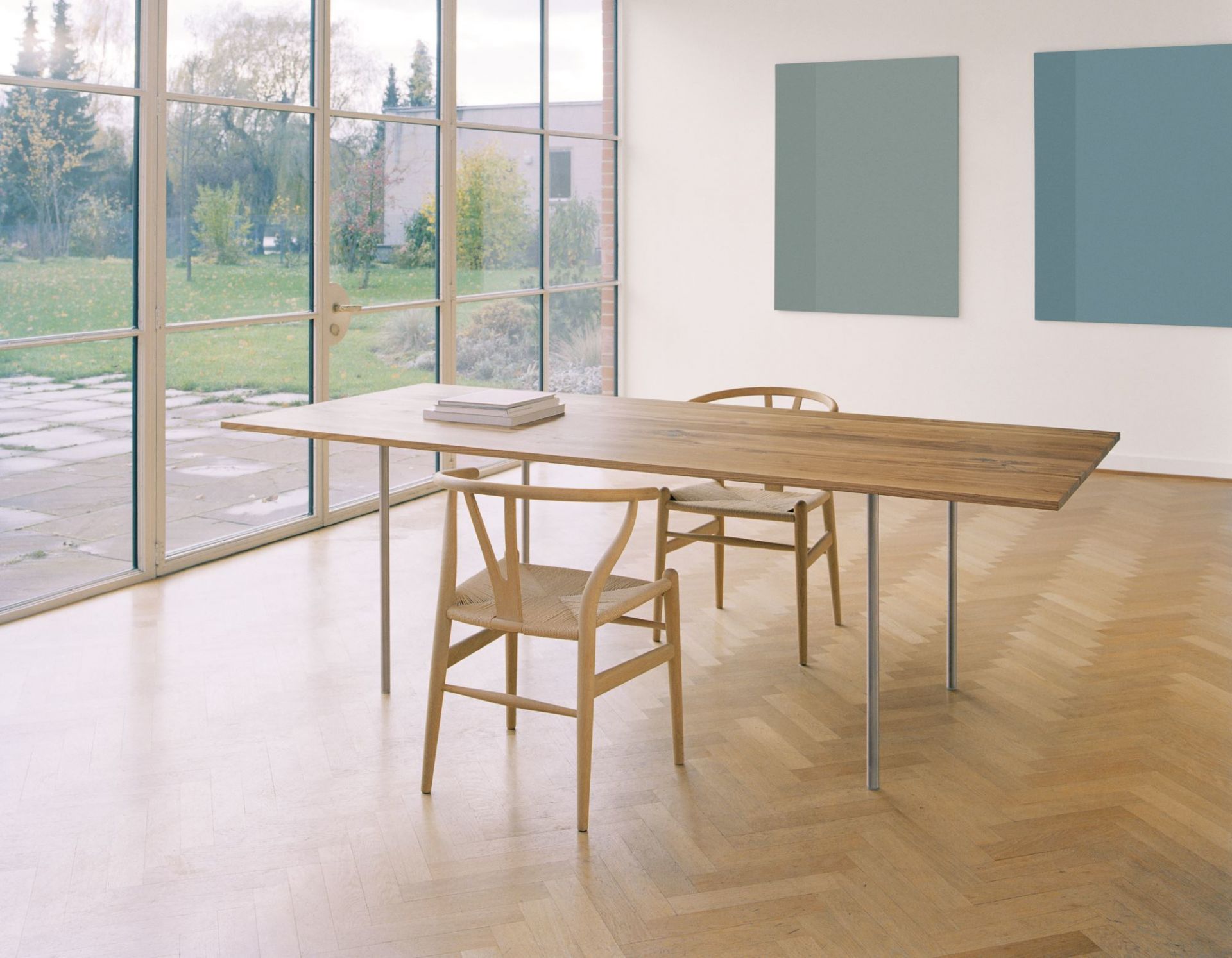 TA14 Anton Tisch e15 aus Massivholz mit Stahlbeinen und zwei Holzstühlen im hellen Raum.