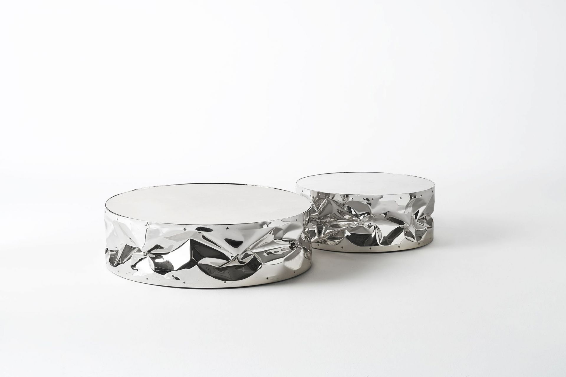Zwei silberne Tab.ulone Couchtische von Opinion Ciatti mit zerknitterter Optik auf weißem Hintergrund.