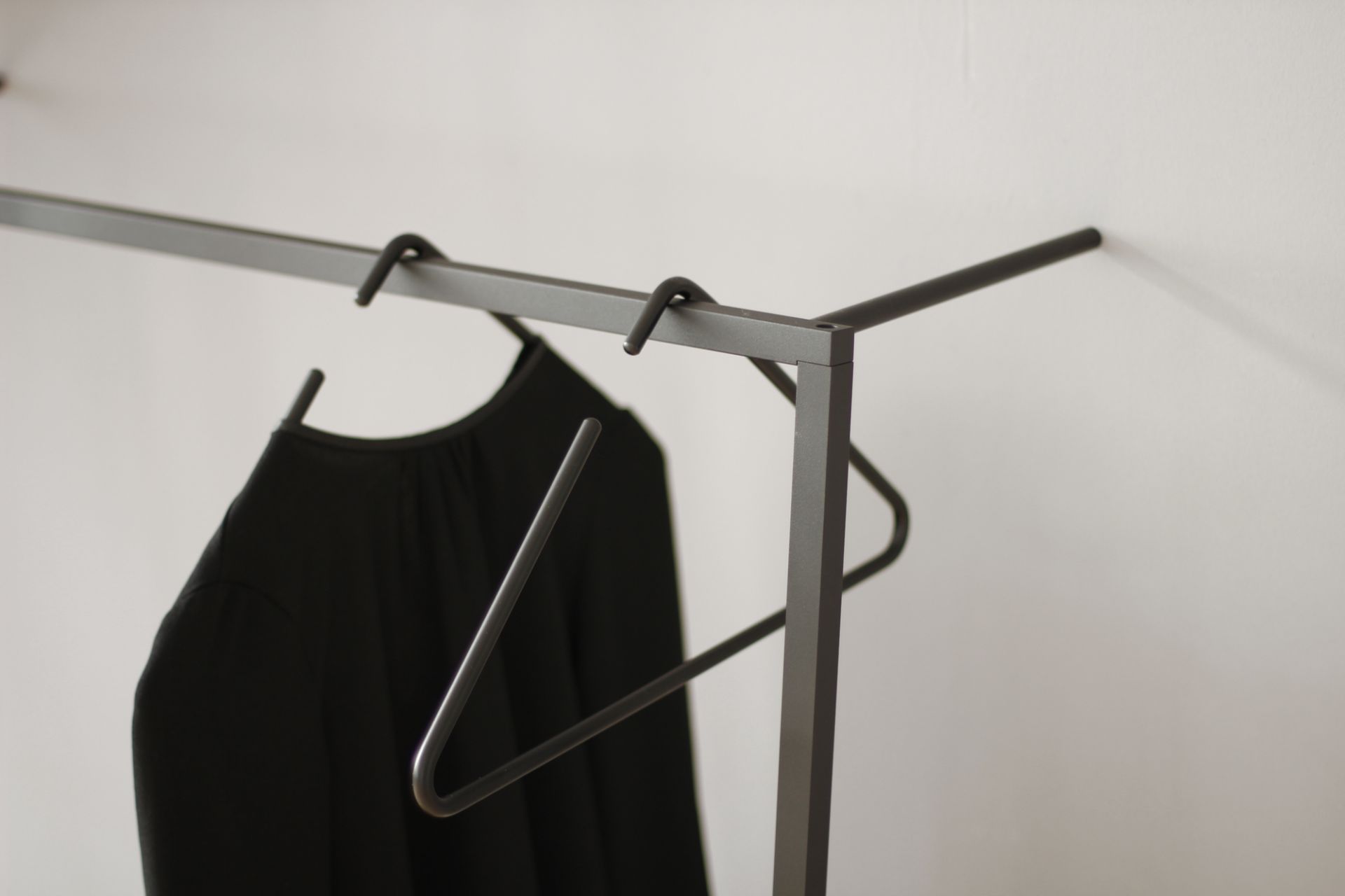 Detailaufnahme: Little Leano Anlehn-Garderobe von Roomsafari mit schwarzem Kleid und minimalistischem Kleiderbügel.