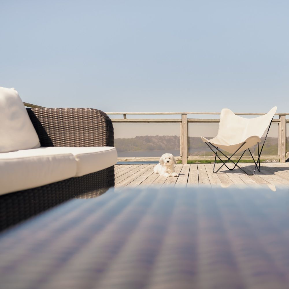 Mariposa Butterfly Chair Outdoor Sessel auf Holzterrasse mit Hund und Sofa.