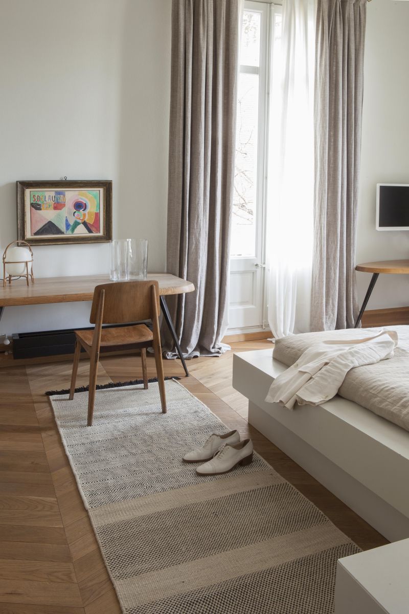 Nanimarquina Tres Stripes Teppich 80x240cm in Schwarz-Beige im Schlafzimmer mit Holzfußboden und weißen Schuhen.