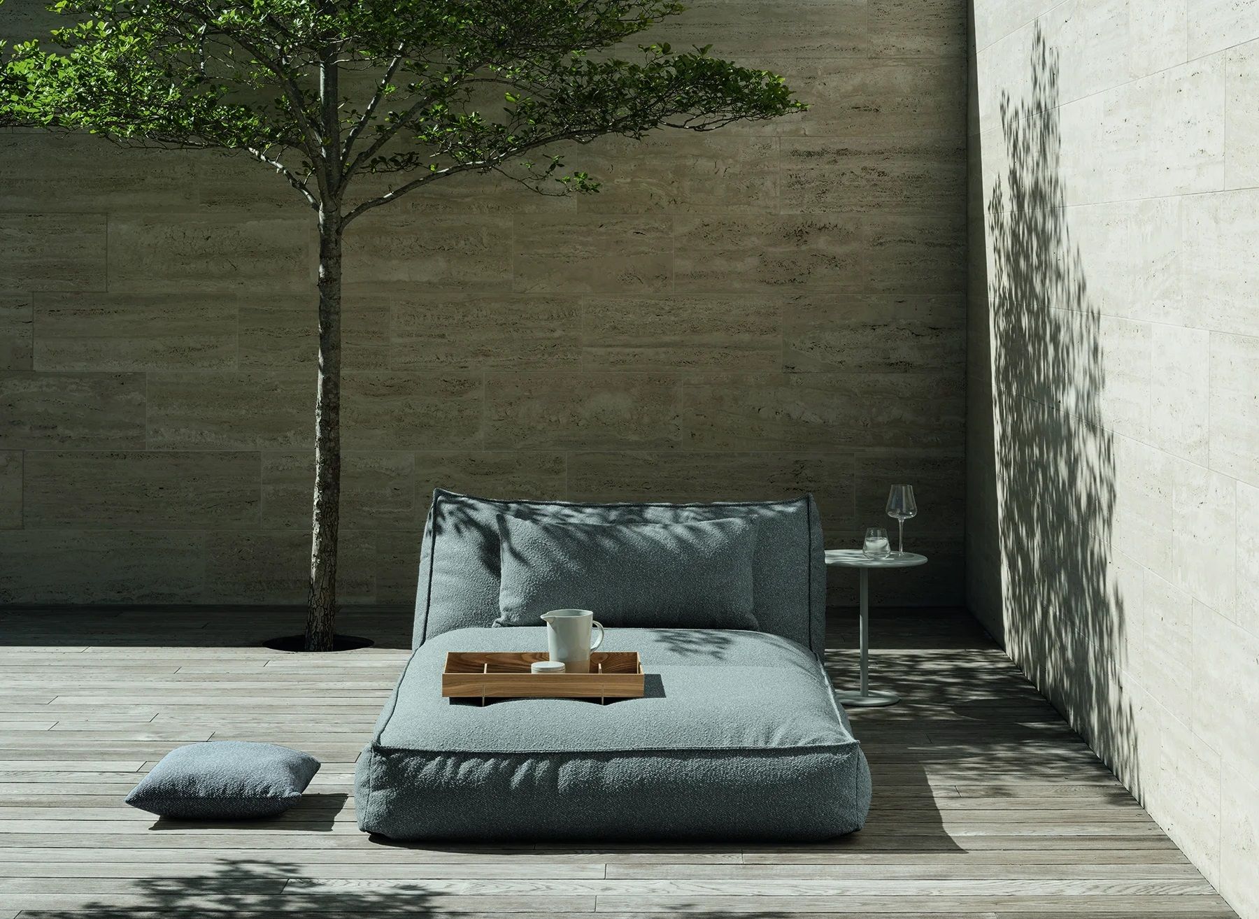 Blomus Stay Tagesbett Outdoor: Graue Outdoor Liege mit Kissen und Tablett auf Holzterrasse.