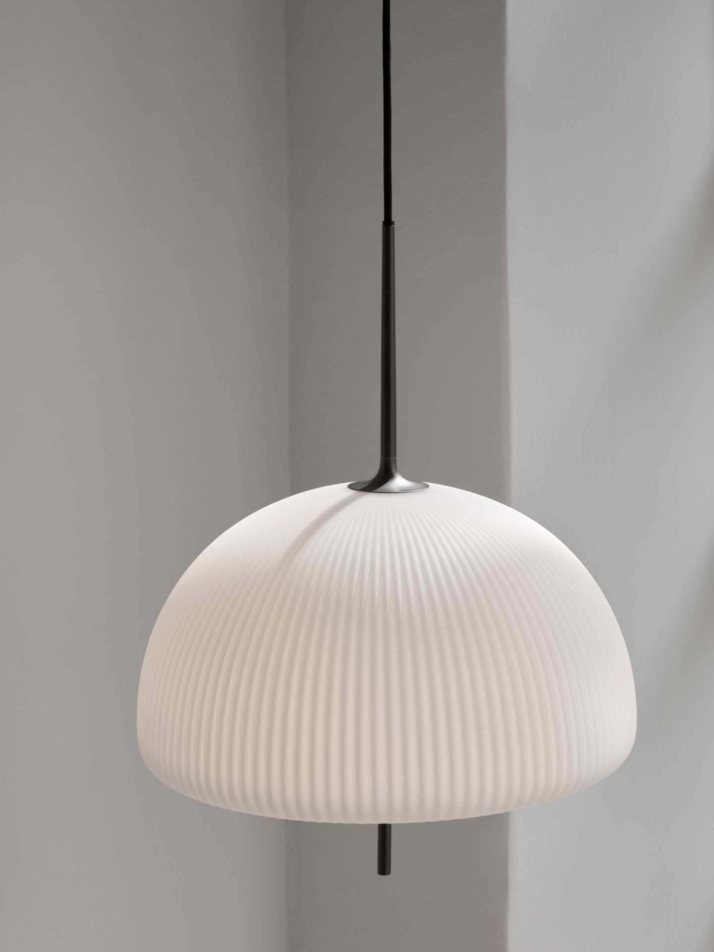 Nahaufnahme der Vipp Sculpture Pendelleuchte: Weißer, gerippter Lampenschirm mit schwarzer Aufhängung.