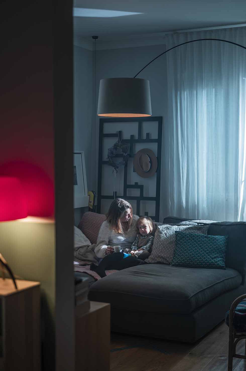 Frau und Kind sitzen unter der Twiggy Bogenleuchte von Foscarini im Wohnzimmer.