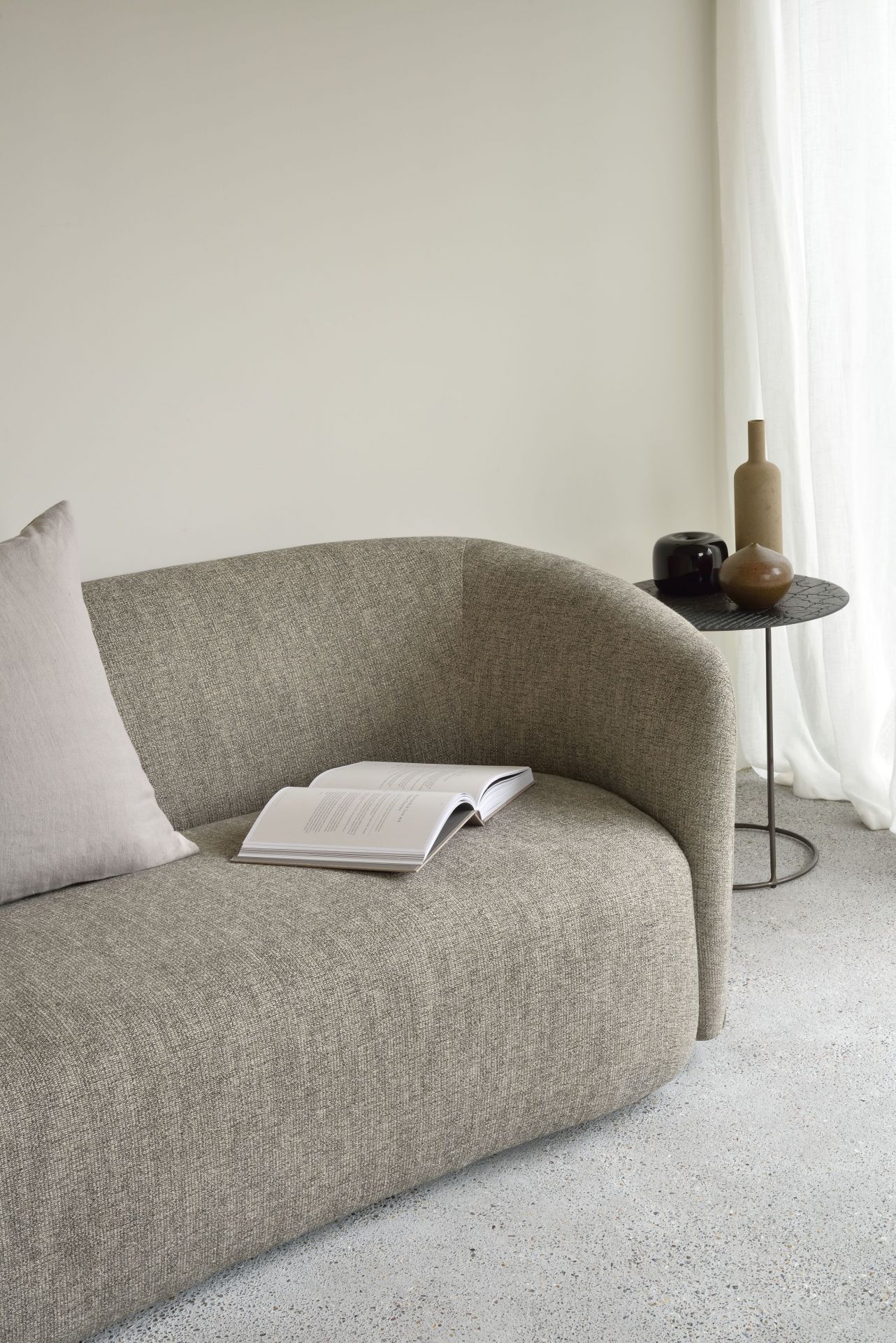 Ellipse Sofa von Ethnicraft: Beige Couch mit Kissen und Buch, minimalistisches Wohnzimmer Design.