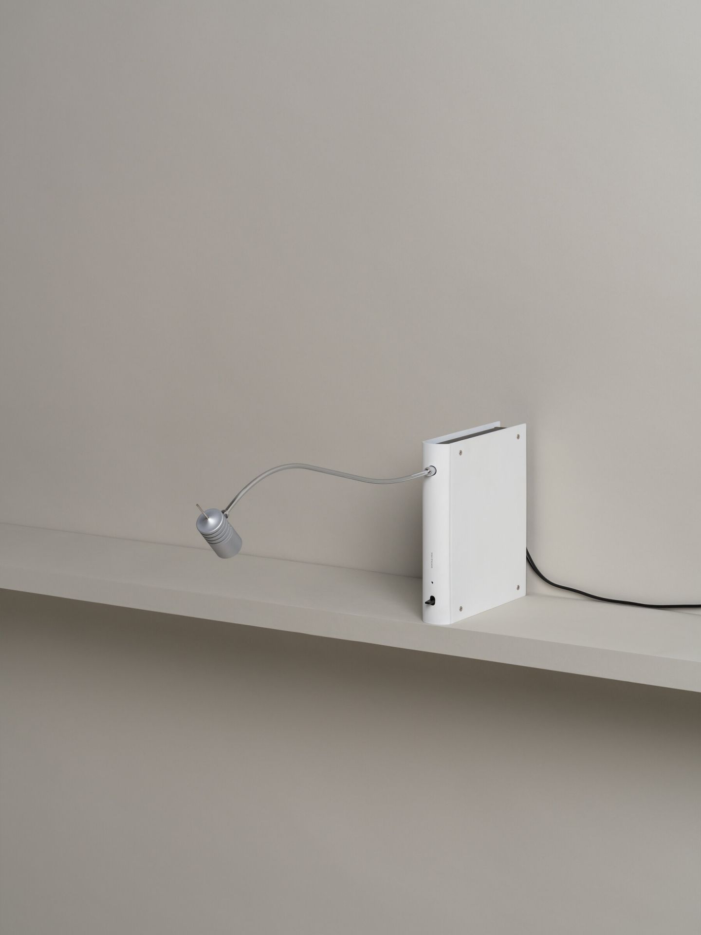 Bib Luz Tischleuchte von Santa & Cole in Off White mit flexiblem Arm auf Regal.