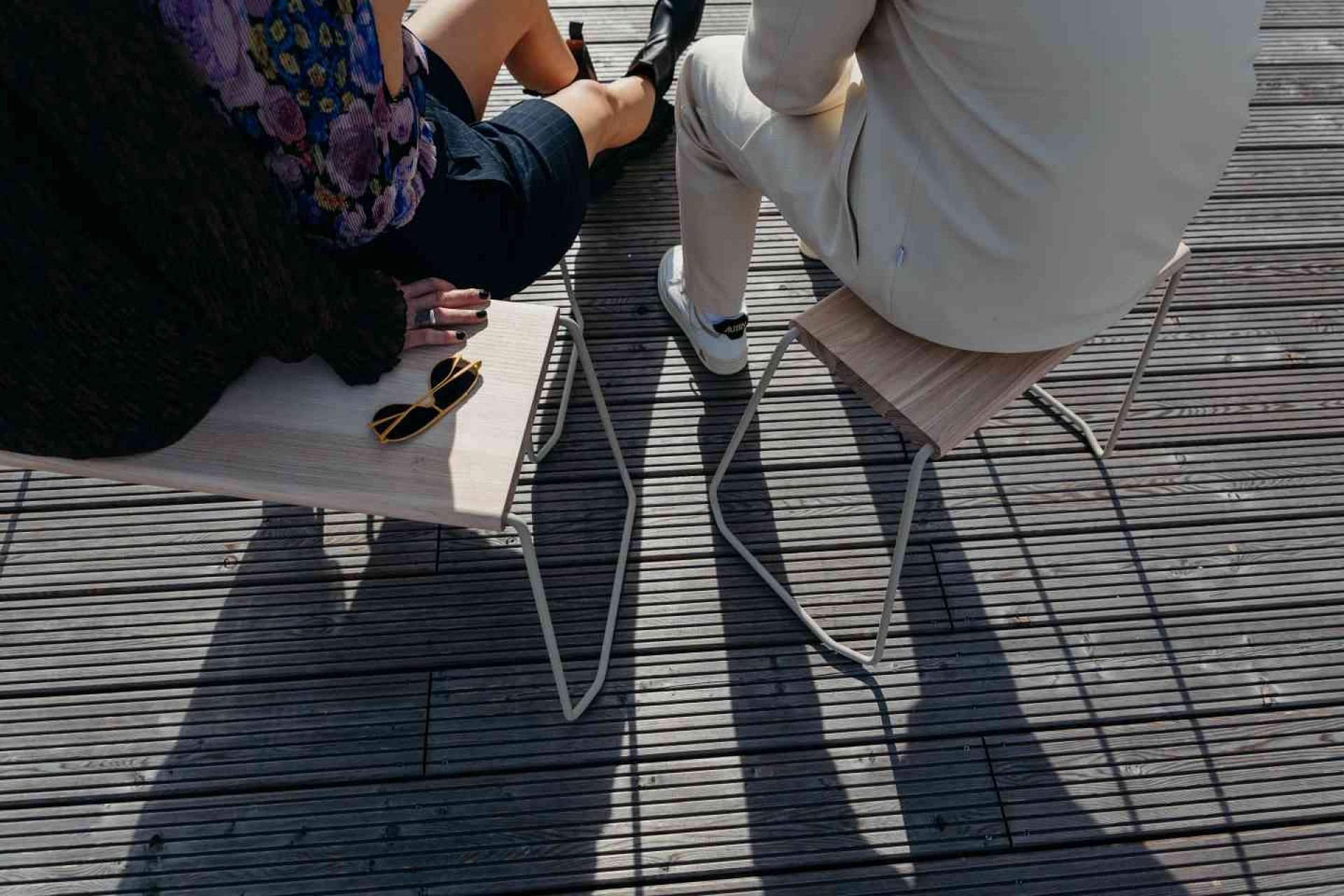 Zwei Personen sitzen auf der weißen D:004 Bank Fuchs & Habicht im Freien.