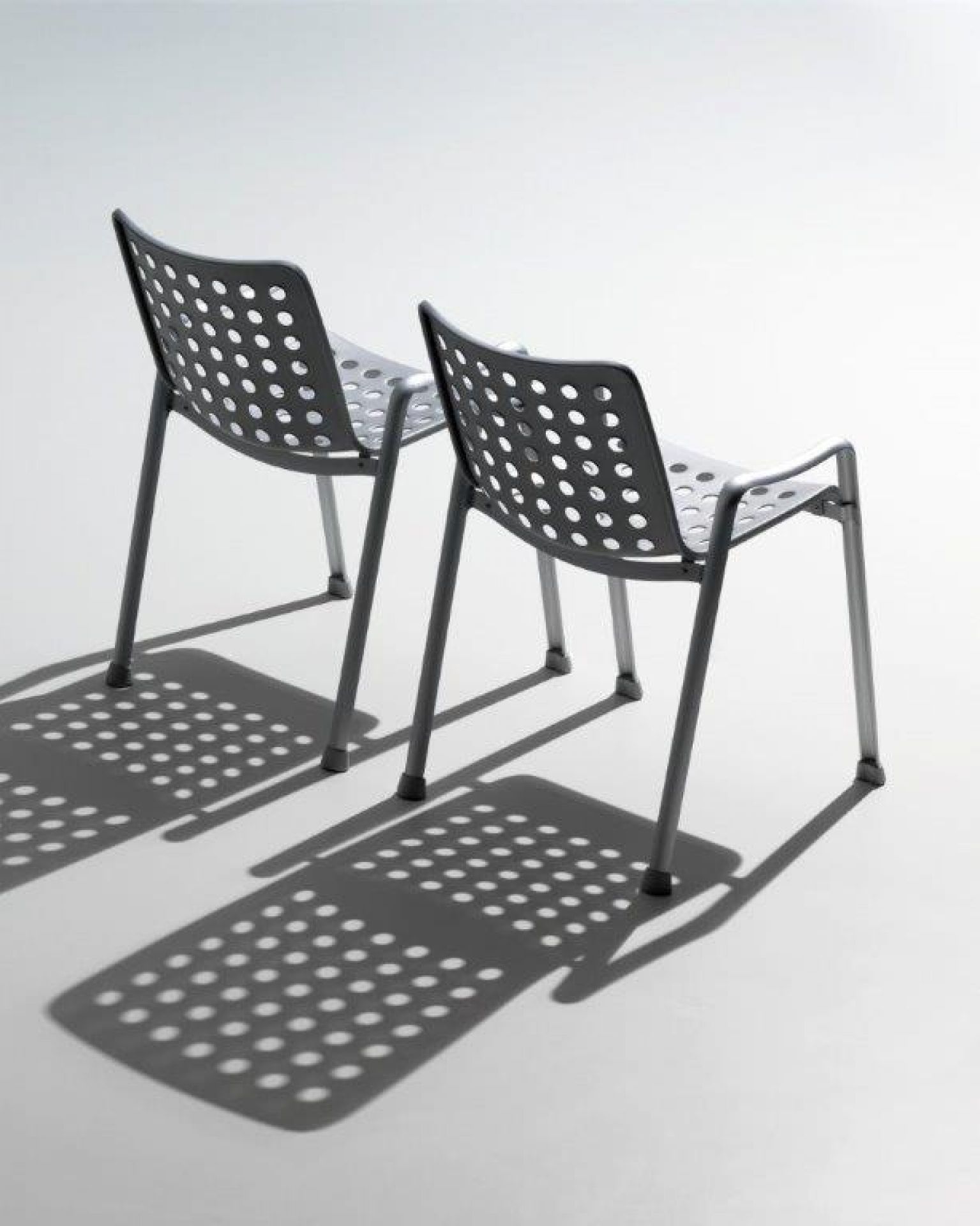 Zwei graue Landi Stühle von Vitra mit runden Löchern im Sitz und Rückenlehne.
