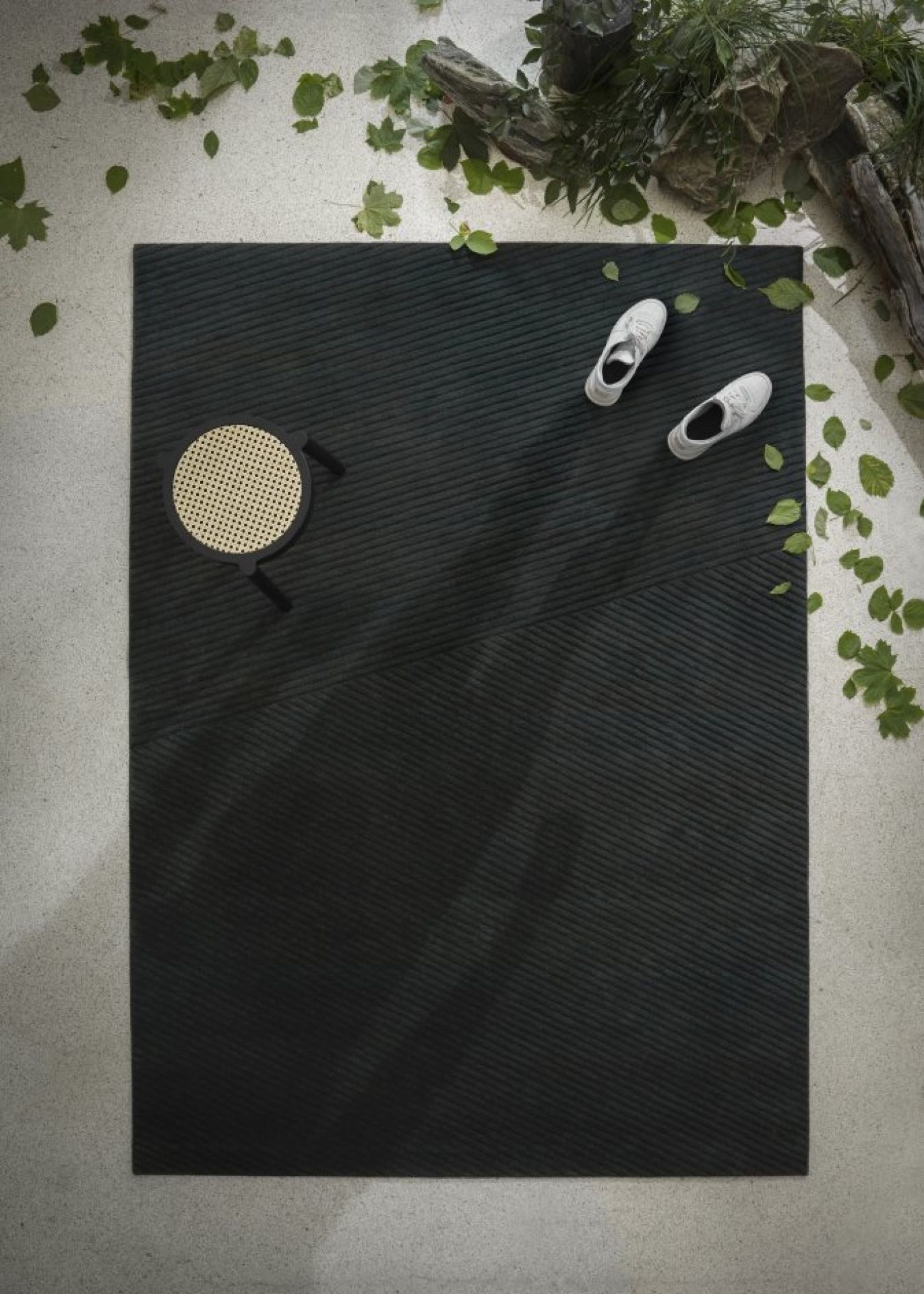 Hellgrauer Row Teppich von Northern, großer, rechteckiger Wollteppich mit dezenter Textur, kombiniert mit Stuhl und Schuhen.