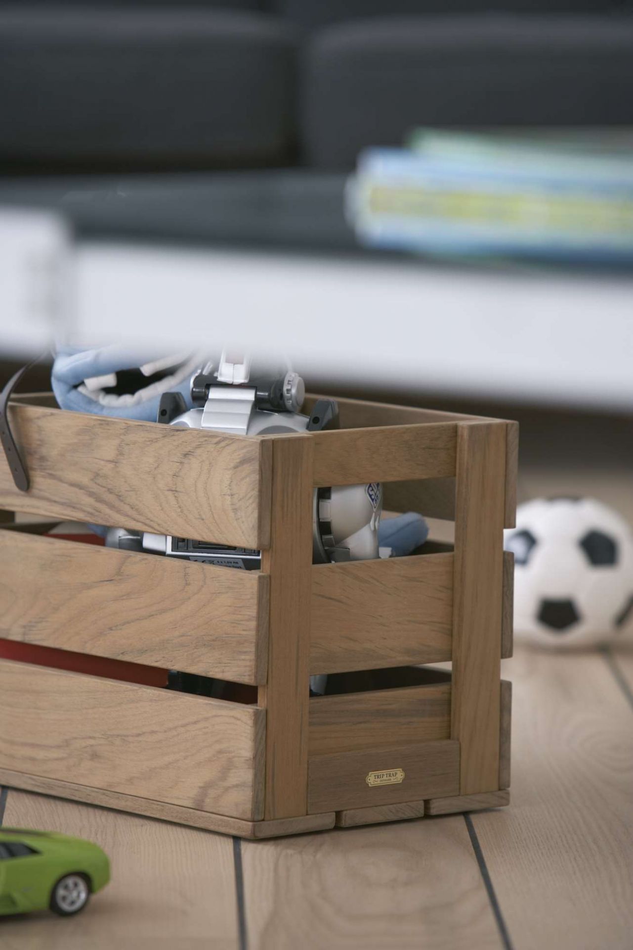 Holzkiste "Dania Box" von Skagerak, gefüllt mit Spielzeug, auf einem Holzboden. Aufbewahrung für Kinderzimmer.