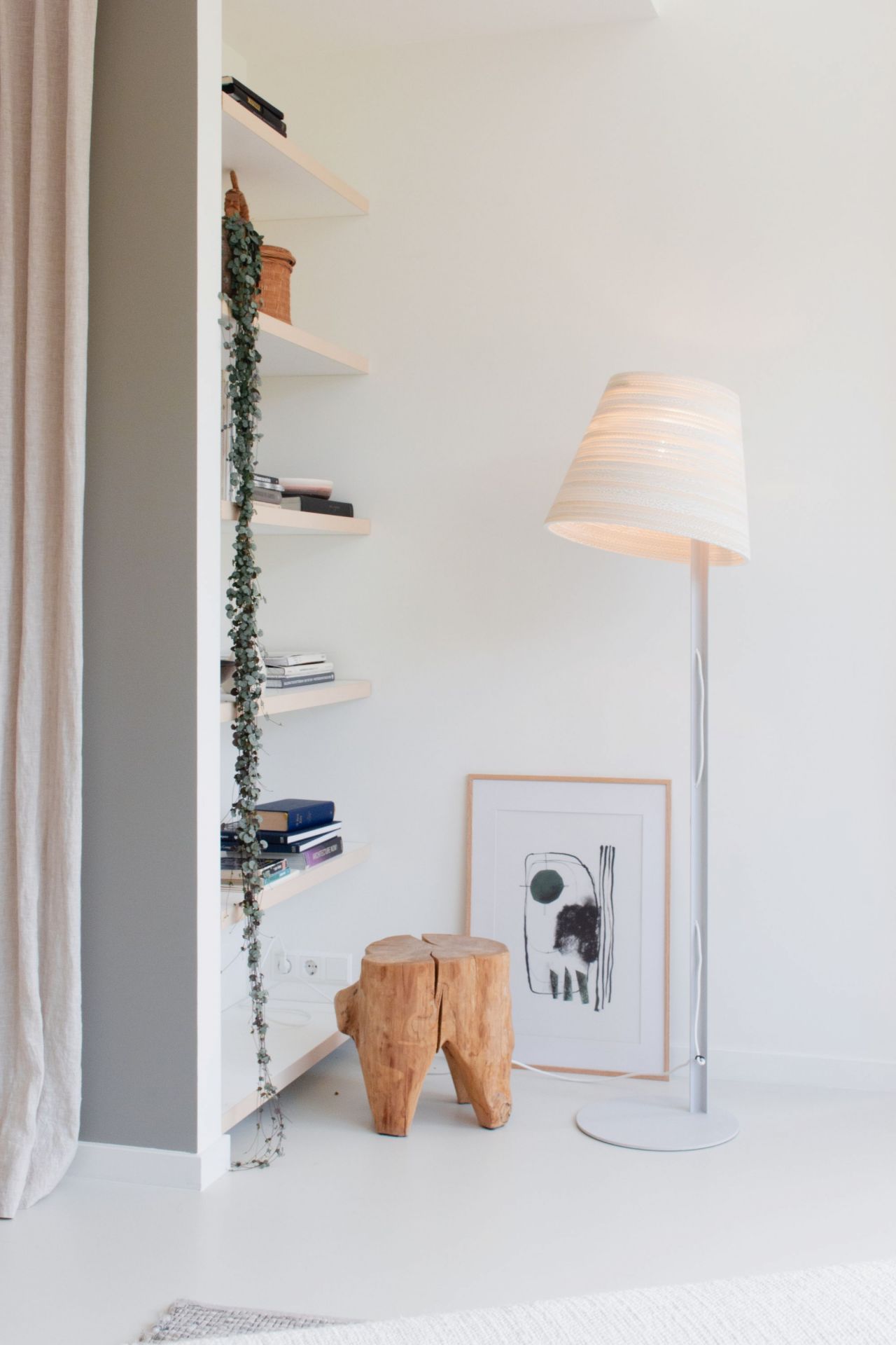 Weiße Tilt Stehleuchte Scraplights von Graypants im modernen Wohnzimmer mit Holzschemel und Regal.