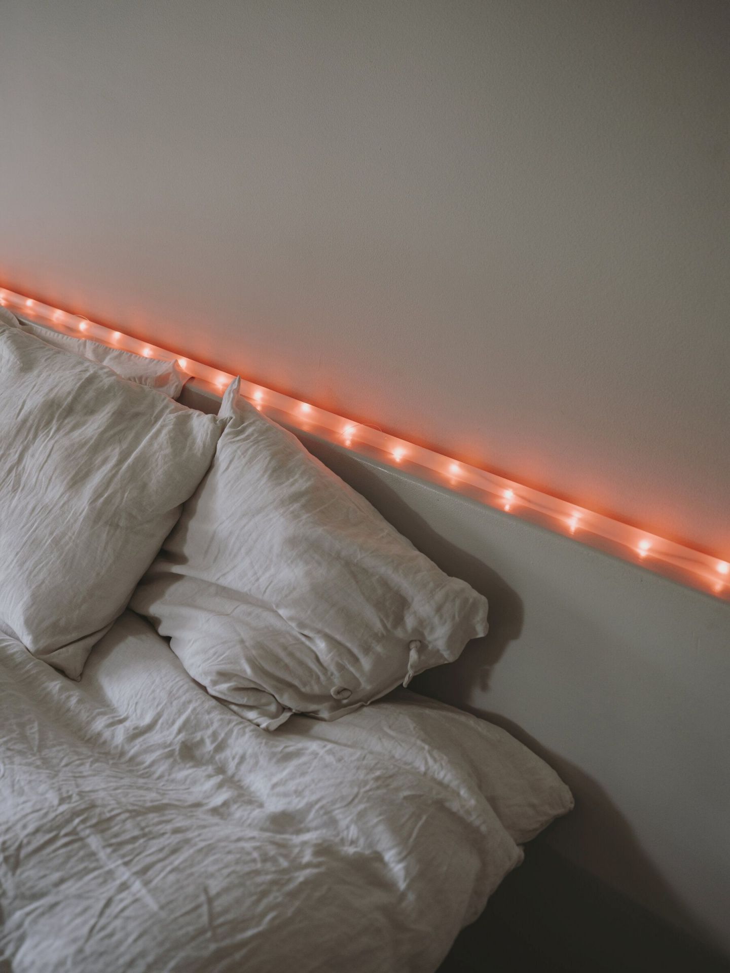 Bett mit Kissen und Santa & Cole La Colilla ähnlicher LED-Lichterkette für stimmungsvolle Beleuchtung.